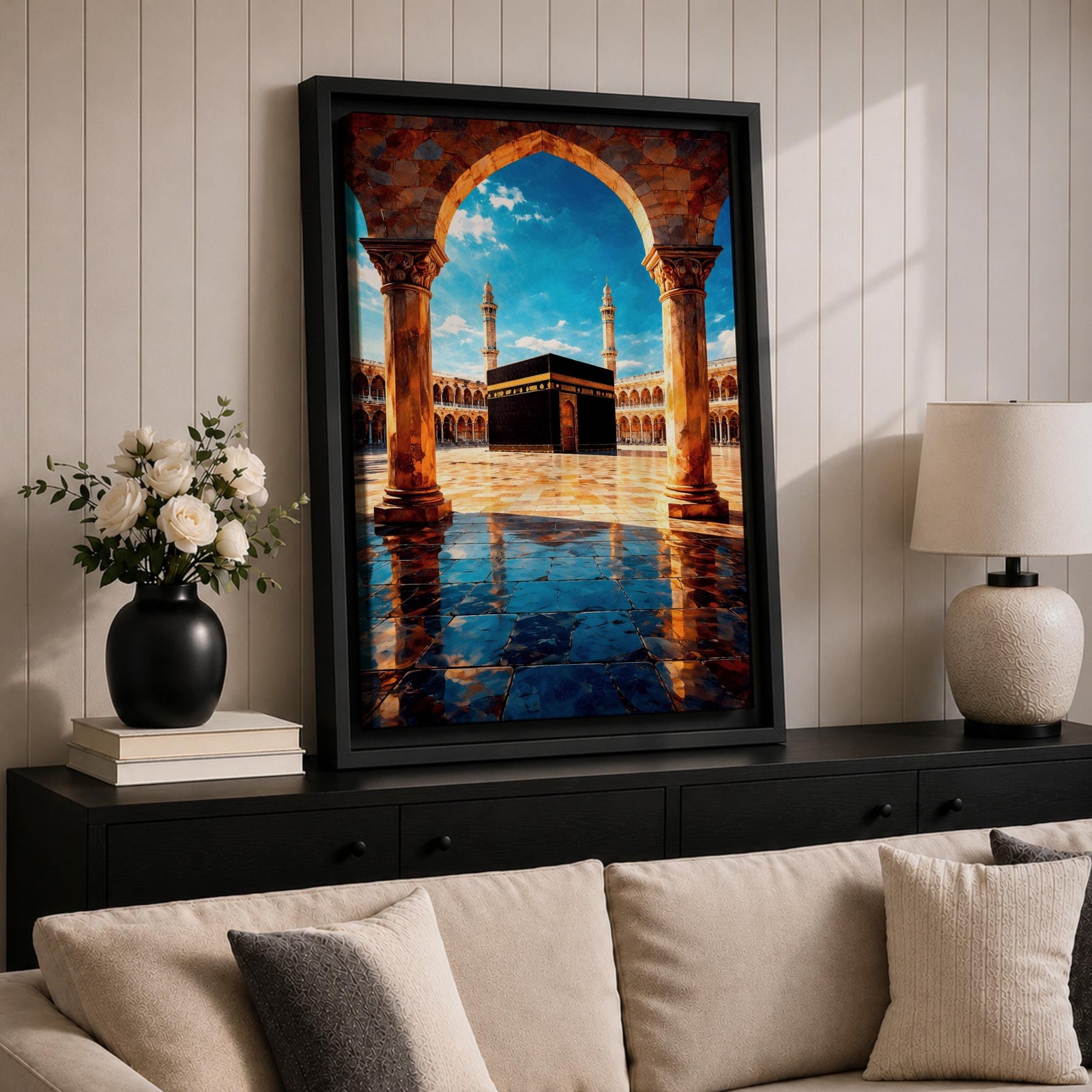 Framed wall art showing the Kaaba at Masjid Al Haram in Mecca viewed through a grand marble archway with columns and reflective courtyard tiles under a bright blue sky.