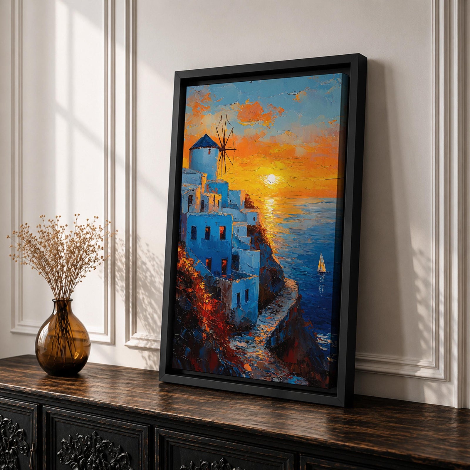 An impasto style framed canvas painting depicting a Santorini sunset over whitewashed buildings with a windmill on a cliffside overlooking the sea. The vibrant sunset sky reflects on the water with a small sailboat visible, capturing a Mediterranean coastal landscape scene with textured brushstrokes.