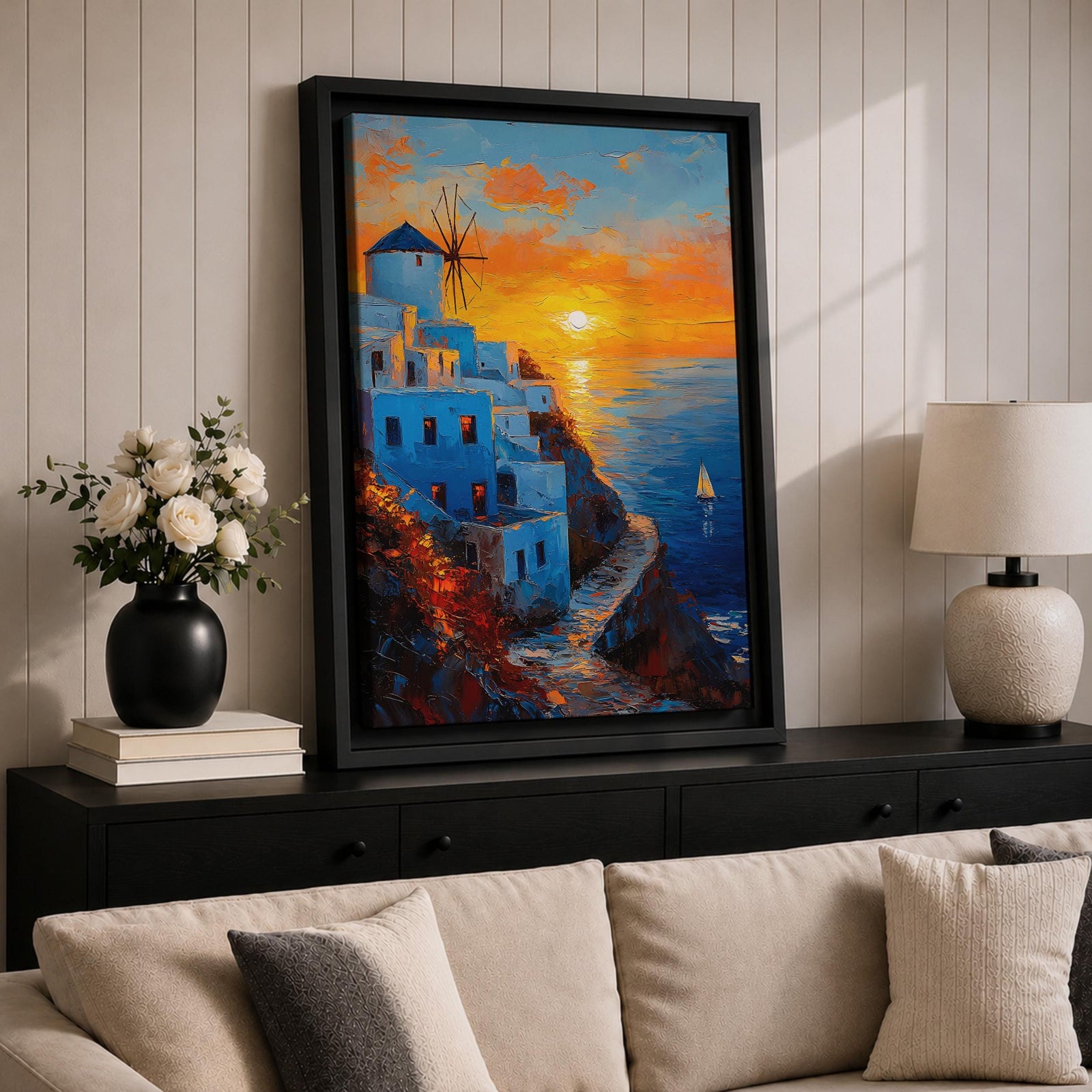 An impasto style framed canvas painting depicting a Santorini sunset over whitewashed buildings with a windmill on a cliffside overlooking the sea. The vibrant sunset sky reflects on the water with a small sailboat visible, capturing a Mediterranean coastal landscape scene with textured brushstrokes.