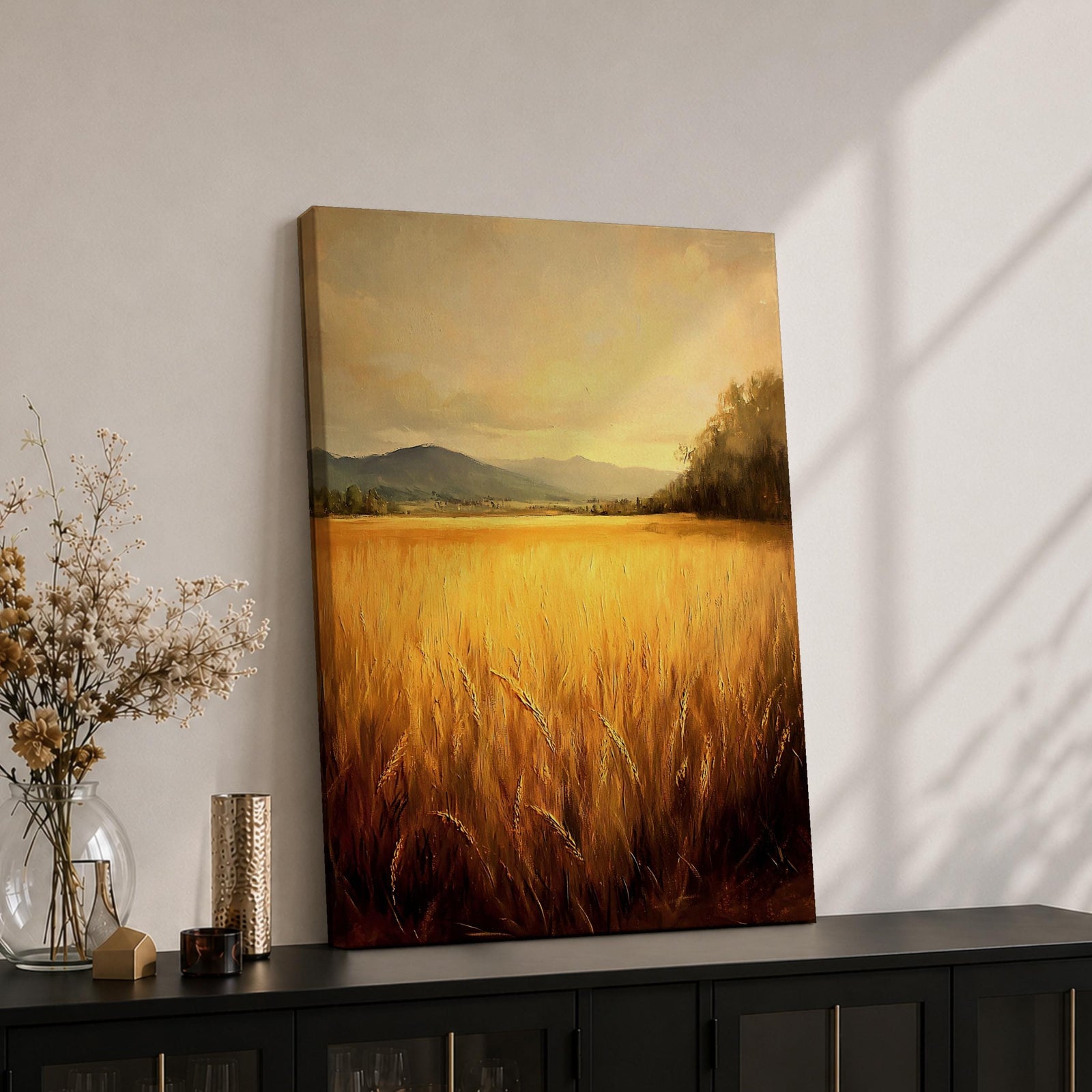 A framed canvas painting depicting a golden wheat field stretching across the foreground with distant hills and trees under a soft sky. The artwork features a vintage style with warm tones and textured brushstrokes emphasizing the natural landscape.
