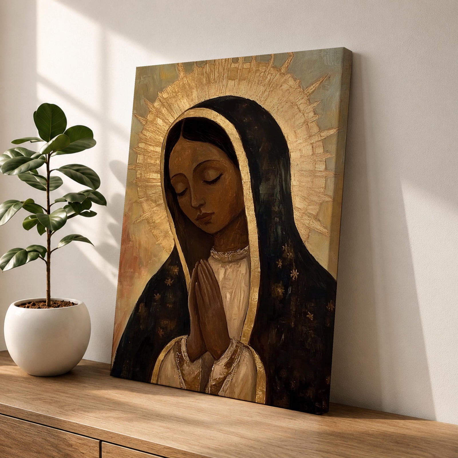 A vintage-style framed canvas painting of Our Lady of Guadalupe depicts the Virgin of Guadalupe with closed eyes and hands clasped in prayer, surrounded by a radiant golden halo. The artwork features traditional Mexican Catholic iconography with a muted color palette and textured brushstrokes.