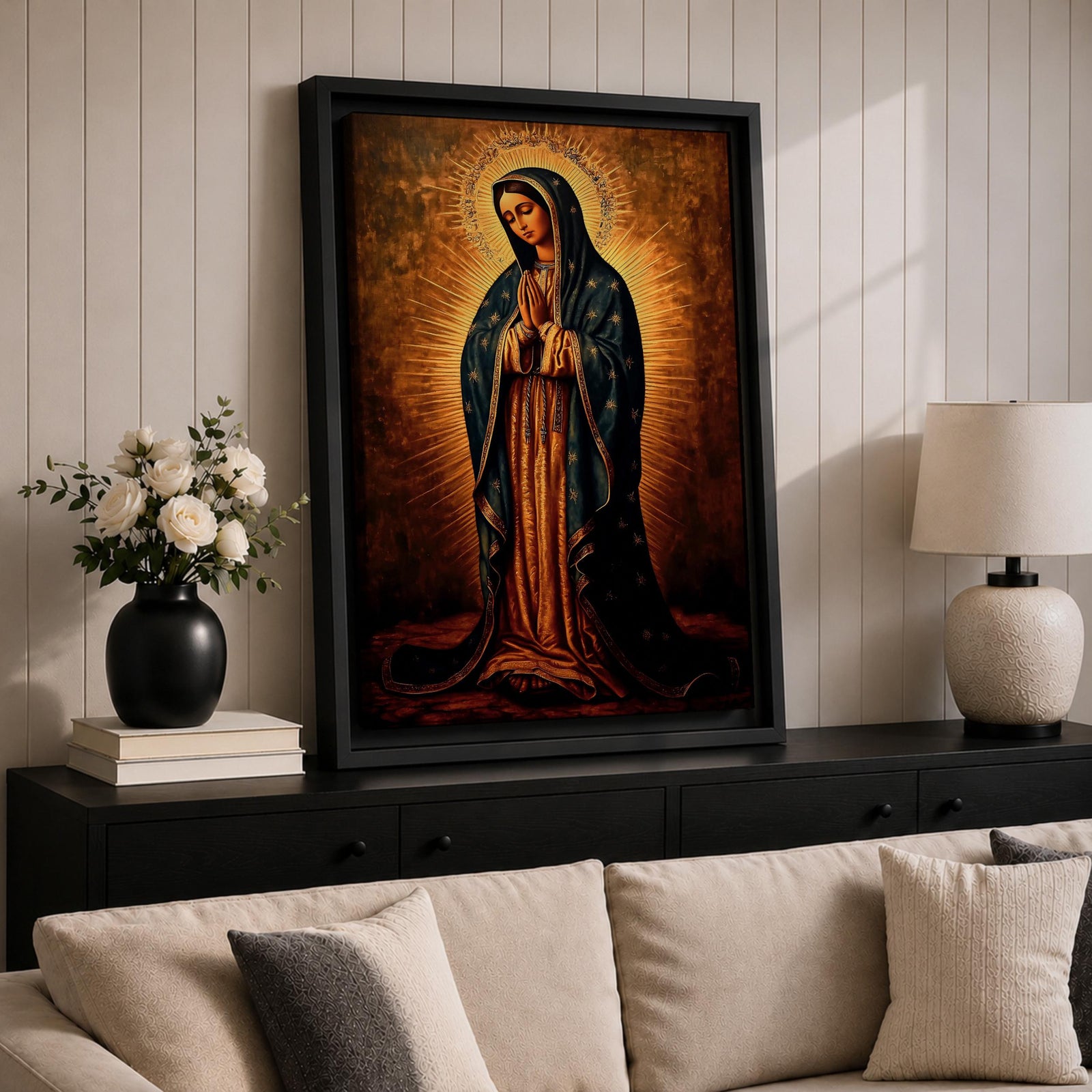 Painting of Our Lady of Guadalupe standing with hands clasped in prayer, wearing a long rose gown and dark star covered mantle, surrounded by radiant golden rays forming a halo behind her figure. The composition presents the Virgin in a traditional devotional icon style with serene expression and symmetrical vertical framing.
