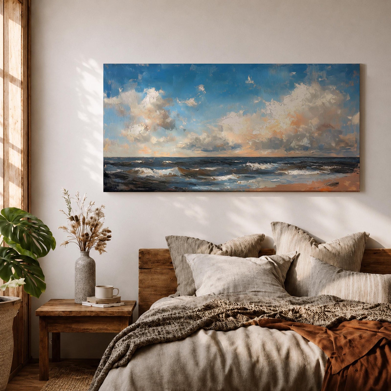 A panoramic seascape painting showing rolling ocean waves moving toward a sandy shoreline beneath a wide sky filled with soft clouds and warm light. The composition stretches across the horizon with textured brushstrokes capturing movement in the water and subtle reflections of blue, white and golden tones across the sea.
