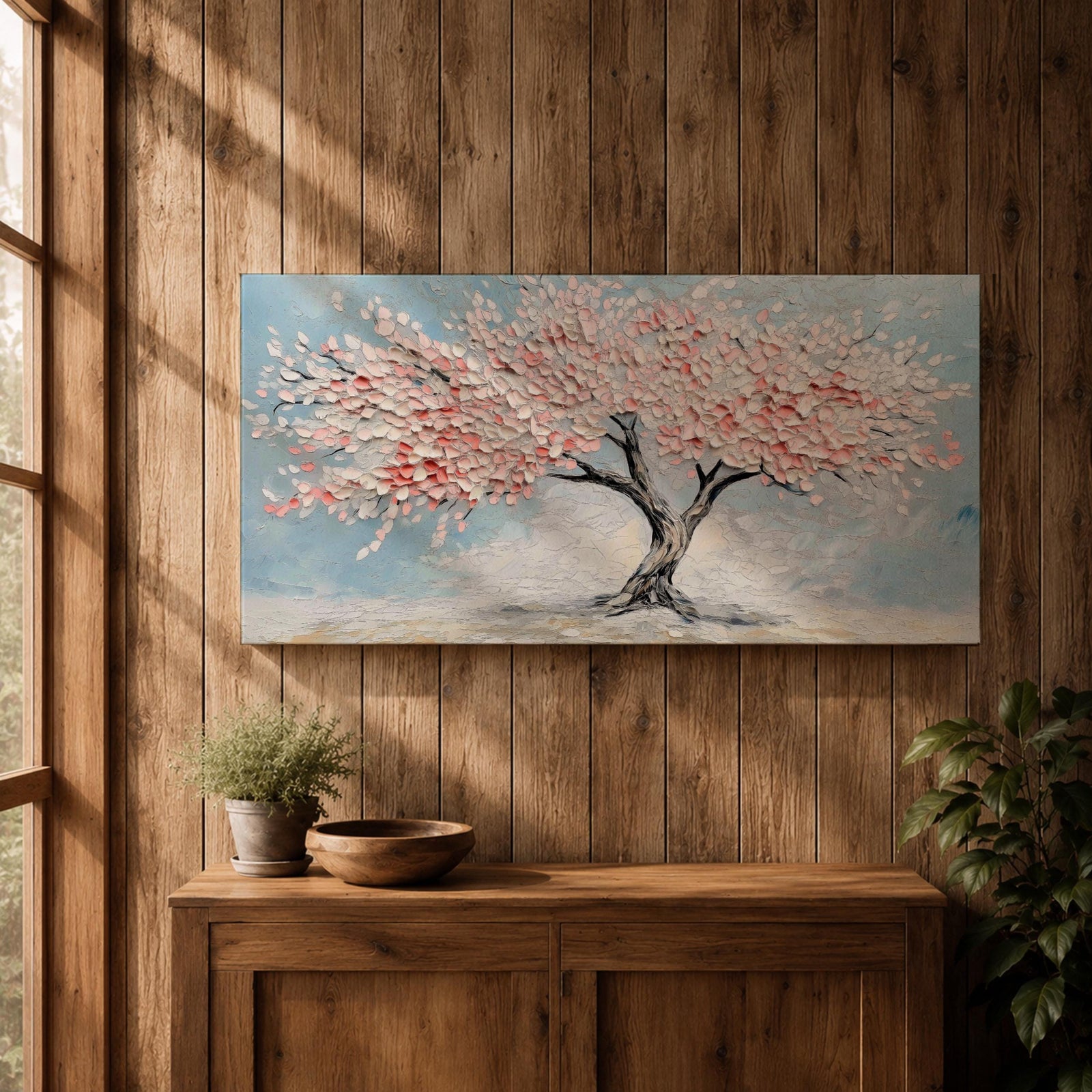 Panoramic textured painting of a cherry blossom tree with a twisting dark trunk and a wide canopy of soft pink blossoms spreading across a pale blue sky. Thick palette knife strokes create layered petals and raised textures, forming a calm spring landscape with delicate floral clusters and gentle pastel tones.