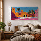 Panoramic painting of a Moroccan kasbah with tall palm trees and arched fortress gates rendered in bold palette knife brushstrokes. Bright orange, pink, and terracotta buildings contrast against a vivid blue sky, capturing the architecture of a Marrakech medina with textured walls and sunlit desert tones.