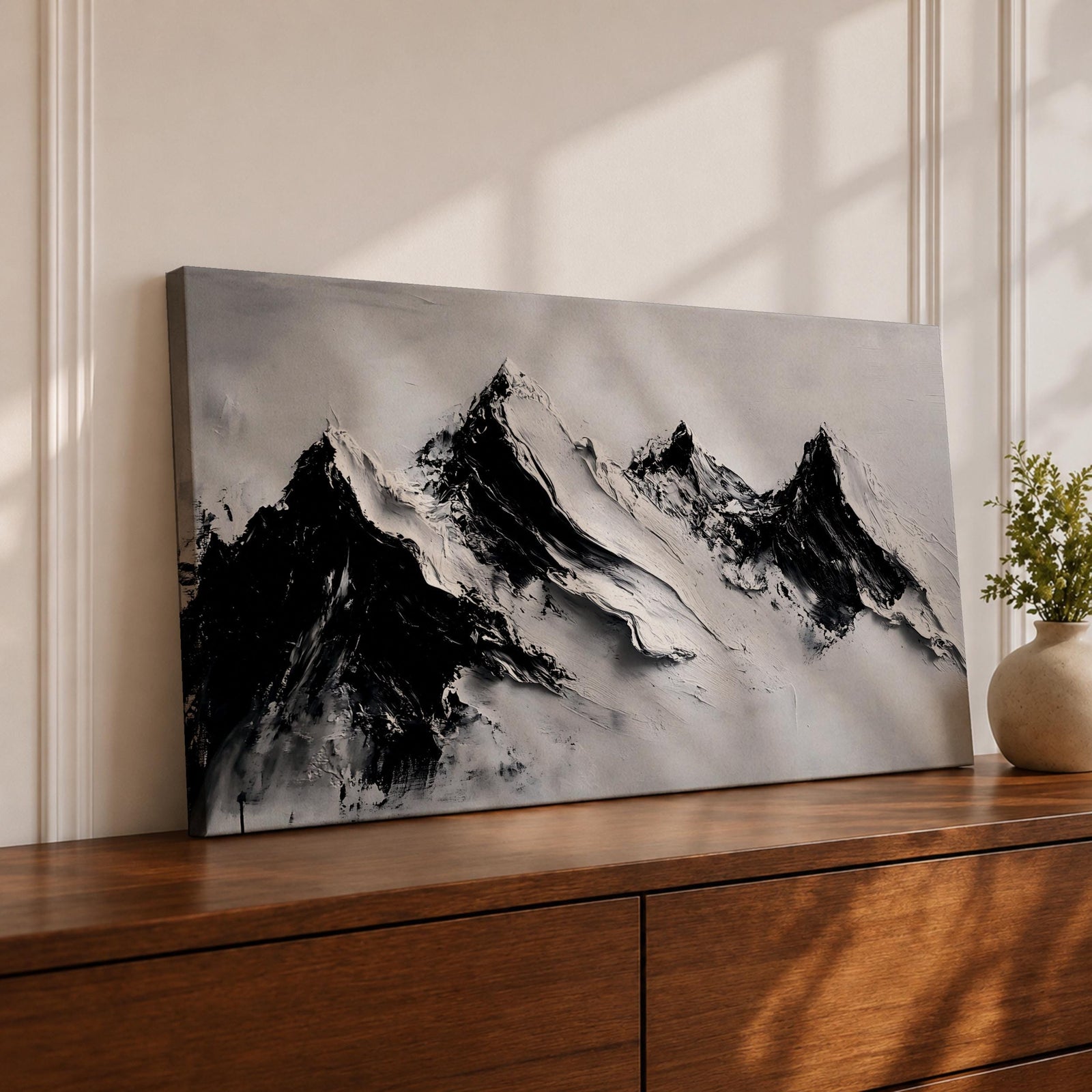 Panoramic black and white painting of alpine peaks with dramatic snowy mountains rising through mist and clouds. Thick textured brushstrokes create strong contrast between dark rocky ridges and bright snowfields, forming a minimalist monochrome mountain landscape stretching across a wide composition.