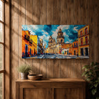Panoramic painting of Oaxaca cathedral rising above a colorful colonial street lined with bright orange and yellow buildings. The historic Mexican architecture features twin cathedral towers beneath a dramatic blue sky with expressive painterly brushstrokes.