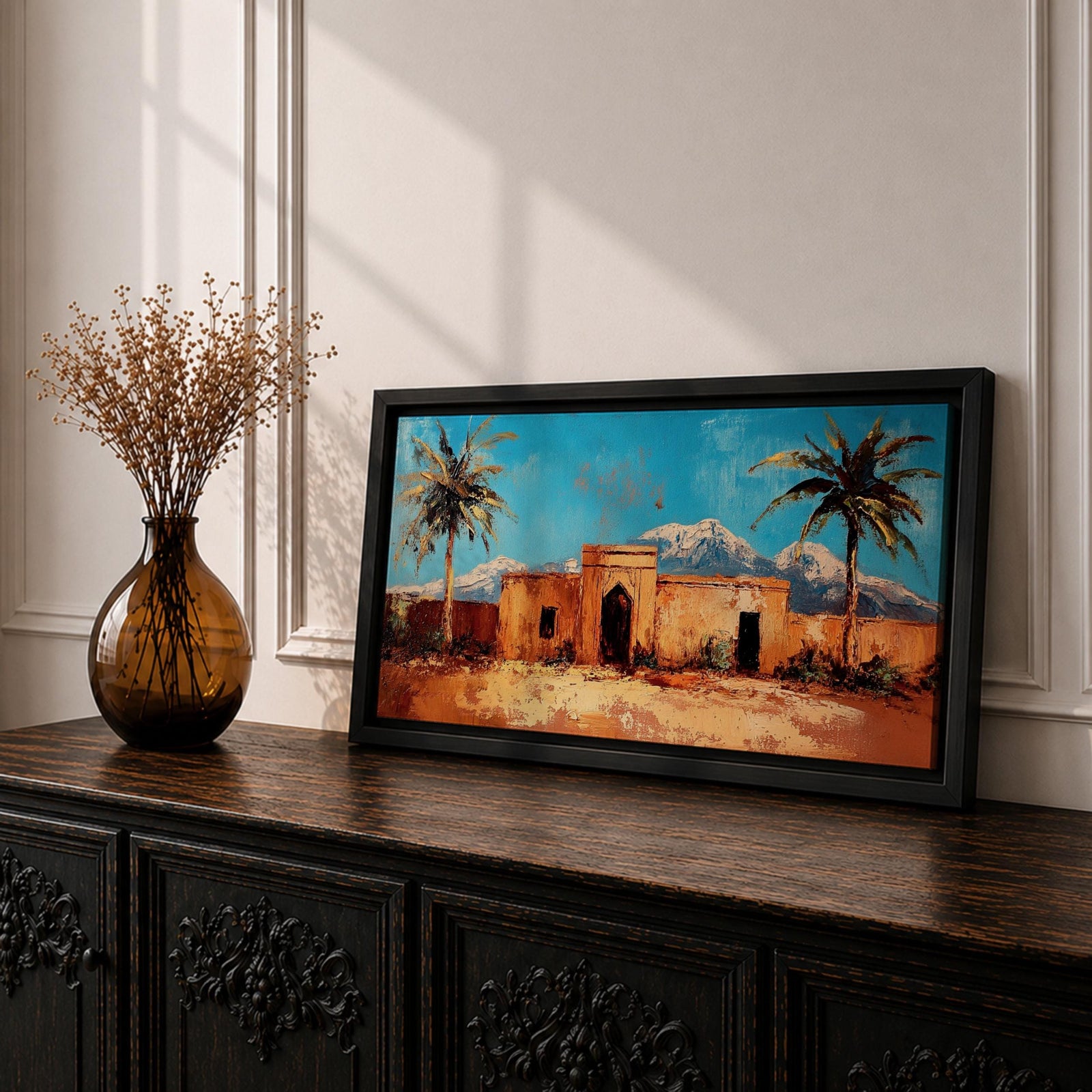 Panoramic painting of a Moroccan kasbah surrounded by palm trees in a desert oasis with the Atlas Mountains rising in the distance. The warm earthen architecture contrasts with a bright blue sky and textured brushstrokes capturing North African landscape scenery.