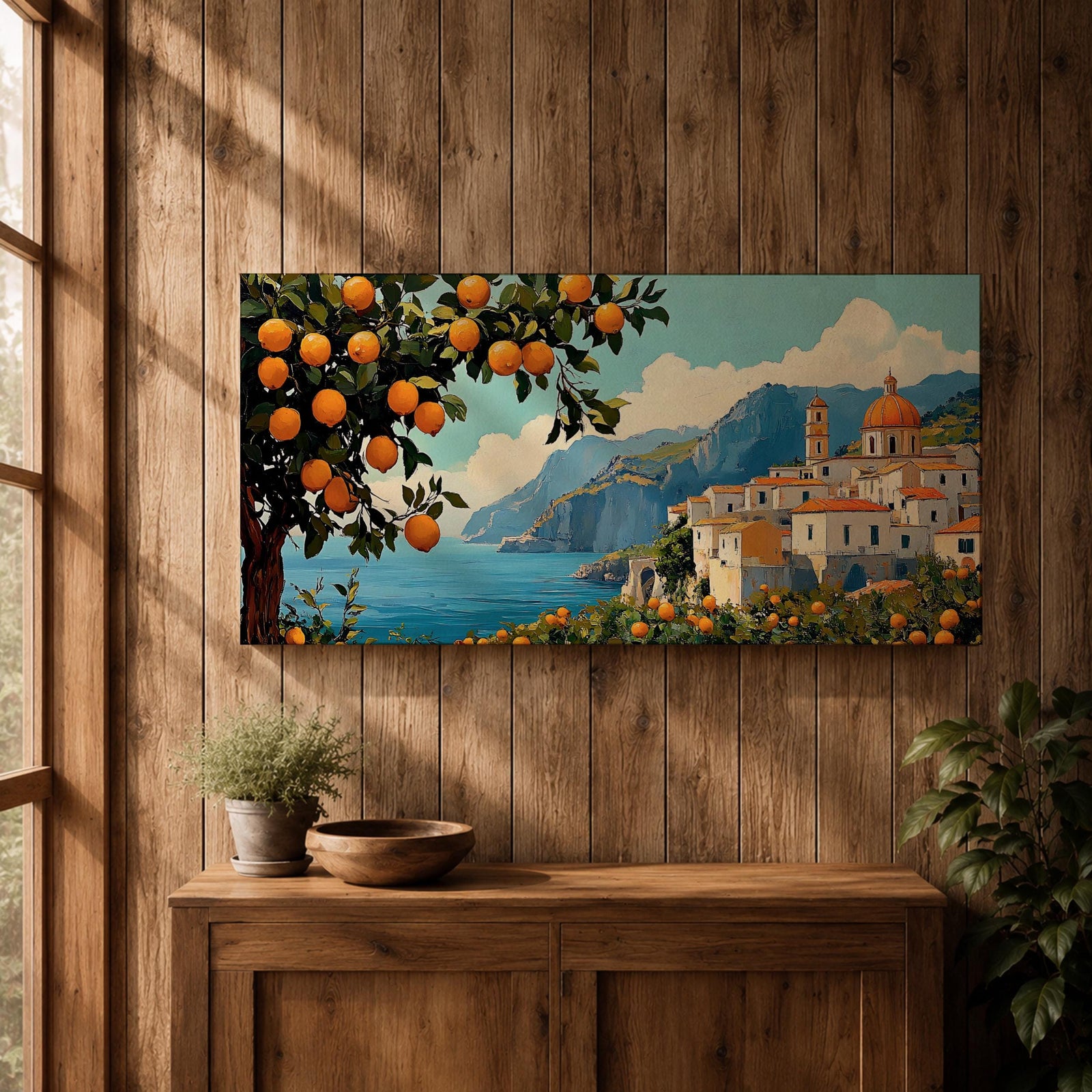Panoramic coastal artwork showing a Mediterranean village overlooking the sea with white buildings and a domed church set against blue mountains. In the foreground a large lemon tree heavy with bright citrus fruit frames the scene while additional lemons and greenery fill the lower landscape, creating a vibrant Amalfi Coast inspired composition.