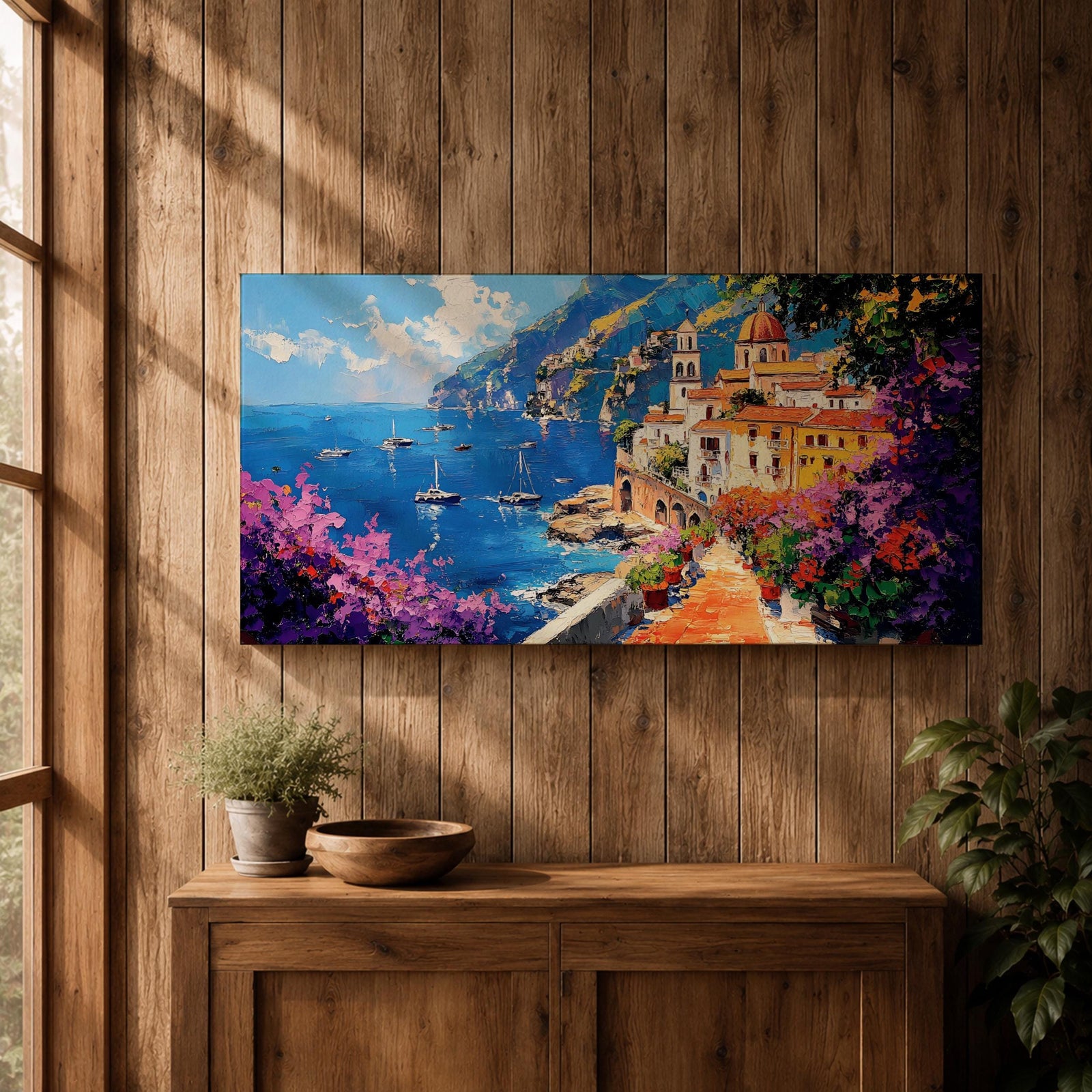 Panoramic painting of the Amalfi Coast featuring a colorful seaside village perched above deep blue Mediterranean water. Boats float across the bay while a stone path lined with blooming bougainvillea leads toward warm sunlit buildings and a domed church, with dramatic coastal cliffs and mountains rising in the distance.