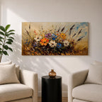 Panoramic painting depicting a vibrant cluster of wildflowers growing through tall meadow grasses. Bright blossoms in orange, blue, purple, and white rise from textured golden stems while loose expressive brushstrokes create movement across the floral arrangement and surrounding field.