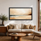 Panoramic coastal landscape painting showing a quiet sandy beach with gentle ocean waves rolling onto the shore beneath a soft sky. Subtle tones of beige, blue, and warm gray create a calm atmosphere while distant hills stretch along the horizon and light reflects across the water.