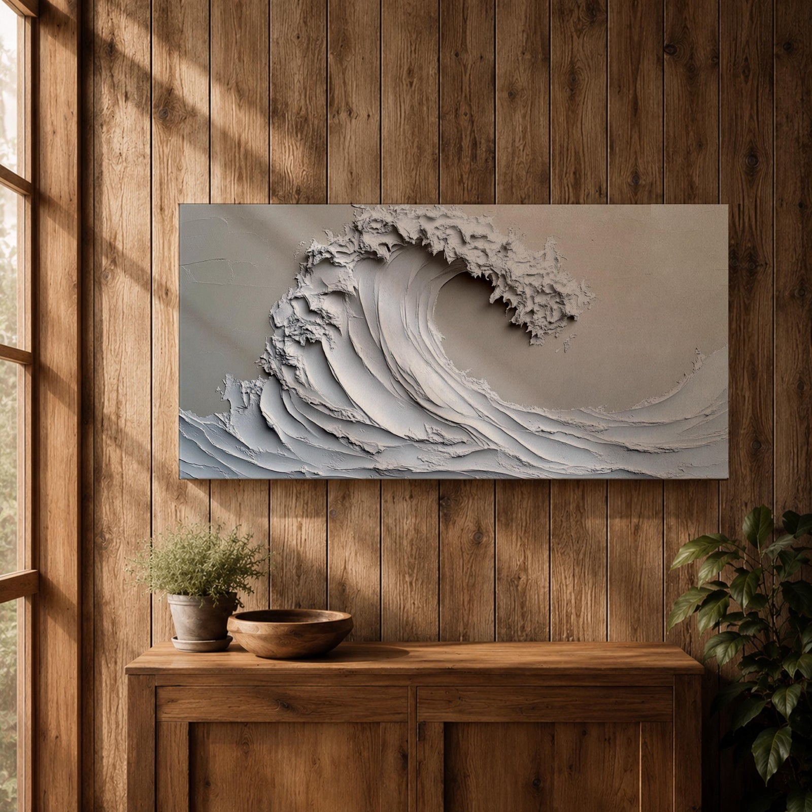 Panoramic textured relief artwork depicting a powerful ocean wave curling upward in sculpted layered forms. The cresting breaker is rendered with thick plaster like ridges and flowing contours in soft neutral tones, creating a minimalist seascape with depth and movement across the wide horizontal composition.