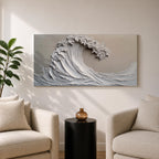 Panoramic textured relief artwork depicting a powerful ocean wave curling upward in sculpted layered forms. The cresting breaker is rendered with thick plaster like ridges and flowing contours in soft neutral tones, creating a minimalist seascape with depth and movement across the wide horizontal composition.