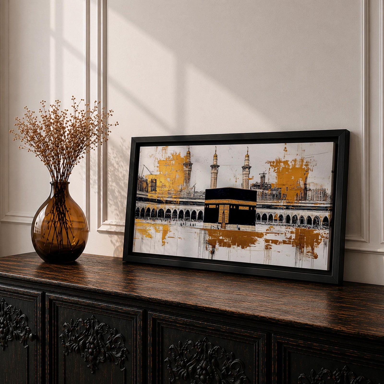 Panoramic painting of the Kaaba in Mecca centered within Masjid al Haram featuring the black cube sanctuary draped in the kiswah with gold calligraphy bands. Tall mosque minarets and long arched colonnades frame the courtyard while bold gold abstract paint textures and layered architectural lines extend across the wide horizontal composition.