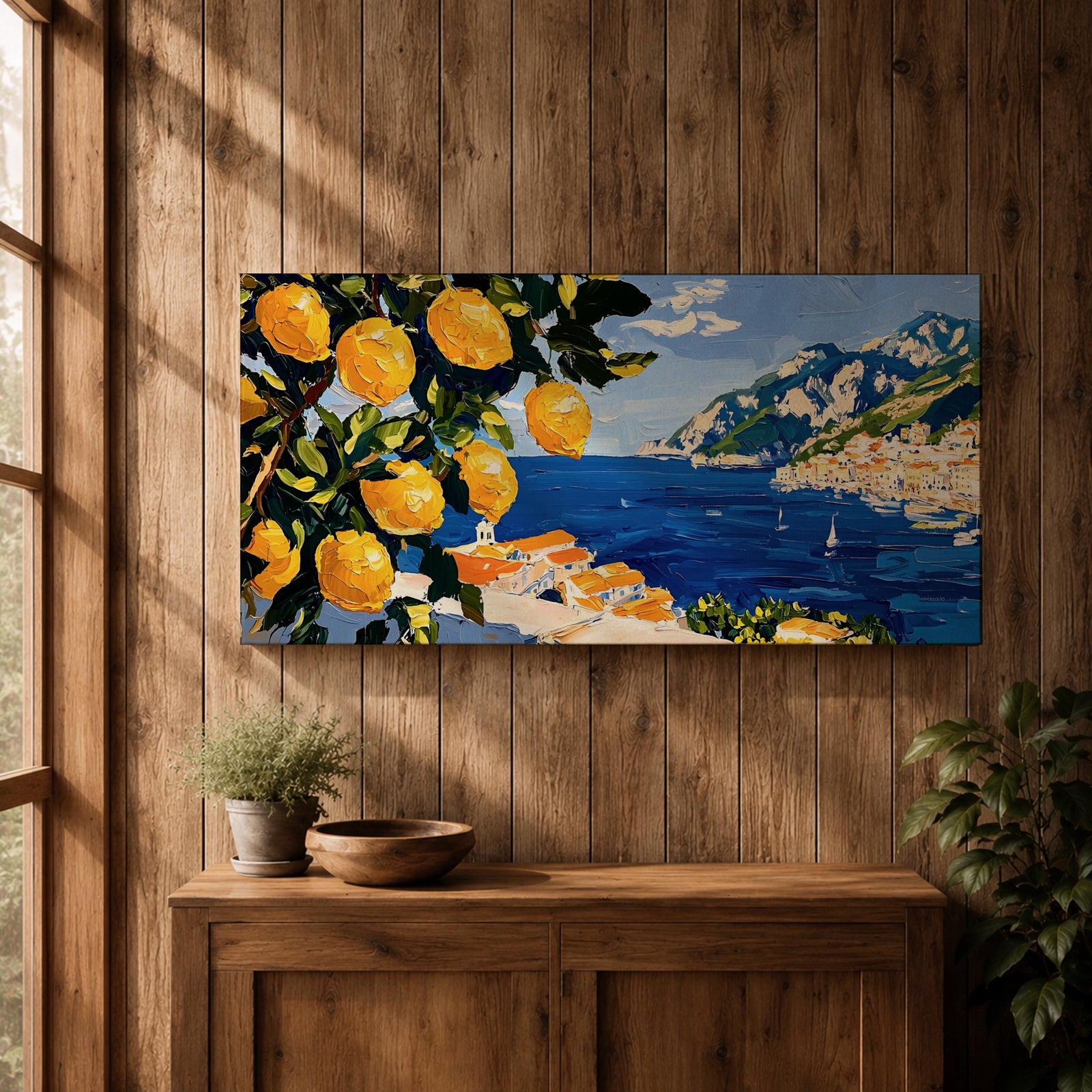 Panoramic painting of bright yellow lemons hanging from leafy branches overlooking the Amalfi Coast with deep blue Mediterranean water, sailboats, and a hillside Italian village with terracotta roofs beneath rugged mountains. Thick palette knife brushstrokes create textured citrus fruit foliage and coastal architecture in a wide landscape composition.