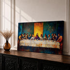 Panoramic painting of the Last Supper showing Jesus seated at the center of a long table surrounded by the twelve apostles. The scene features expressive brush textures with deep blue and warm gold tones while a glowing light behind Christ creates a strong focal point across the wide horizontal composition.