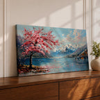 Panoramic painting of a cherry blossom tree in full bloom beside a calm mountain lake with snow covered peaks in the distance and soft clouds above. Pink petals drift across the water while thick palette knife brushstrokes create texture in the blossoms shoreline and reflections forming a wide spring landscape scene with bold color contrast.