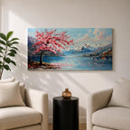 Panoramic painting of a cherry blossom tree in full bloom beside a calm mountain lake with snow covered peaks in the distance and soft clouds above. Pink petals drift across the water while thick palette knife brushstrokes create texture in the blossoms shoreline and reflections forming a wide spring landscape scene with bold color contrast.