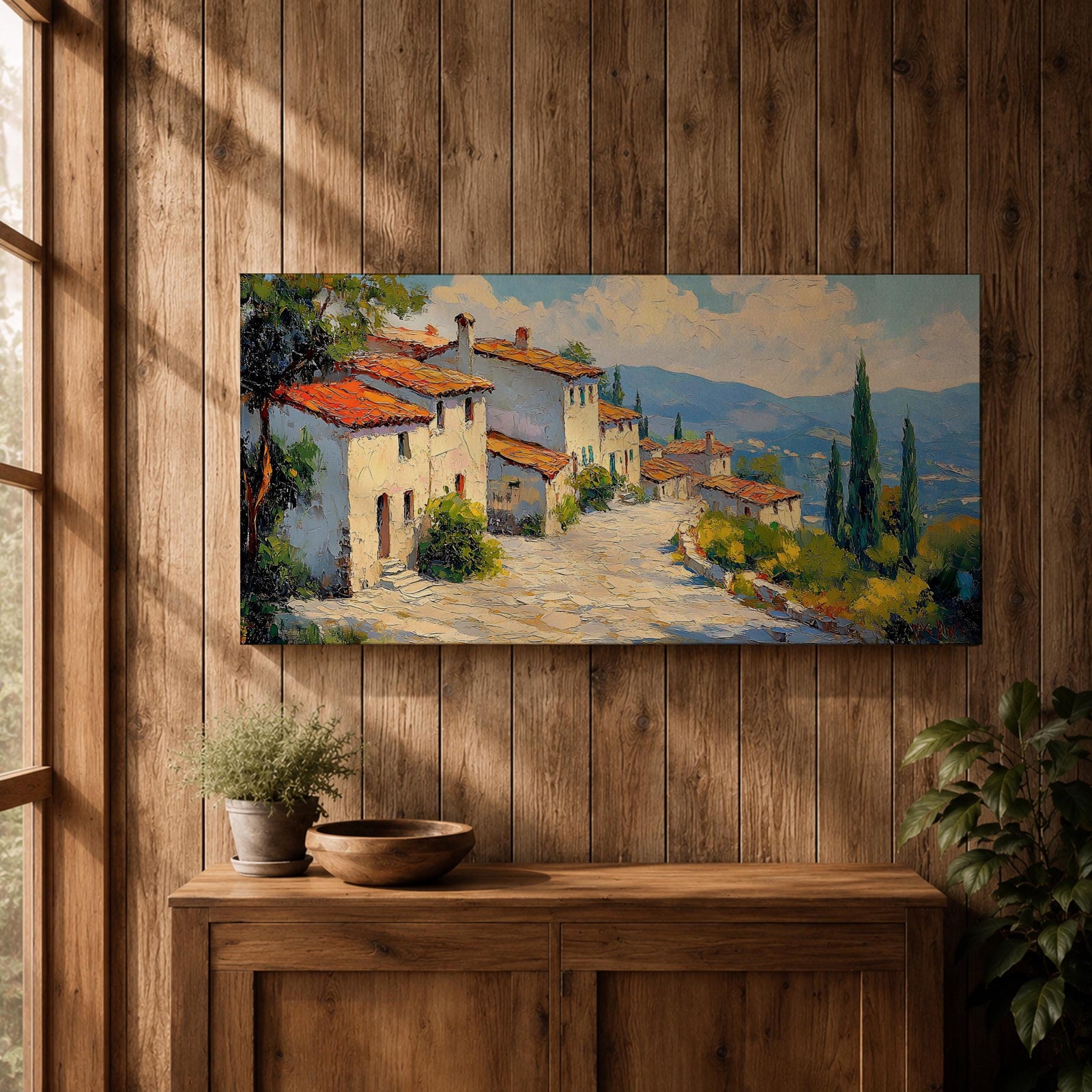 Panoramic painting of a Mediterranean hillside village with warm stone houses and terracotta roofs overlooking the rolling Tuscany hills. Thick palette knife brushstrokes create textured buildings cypress trees and layered green landscapes beneath a glowing sky forming a wide Italian countryside scene.