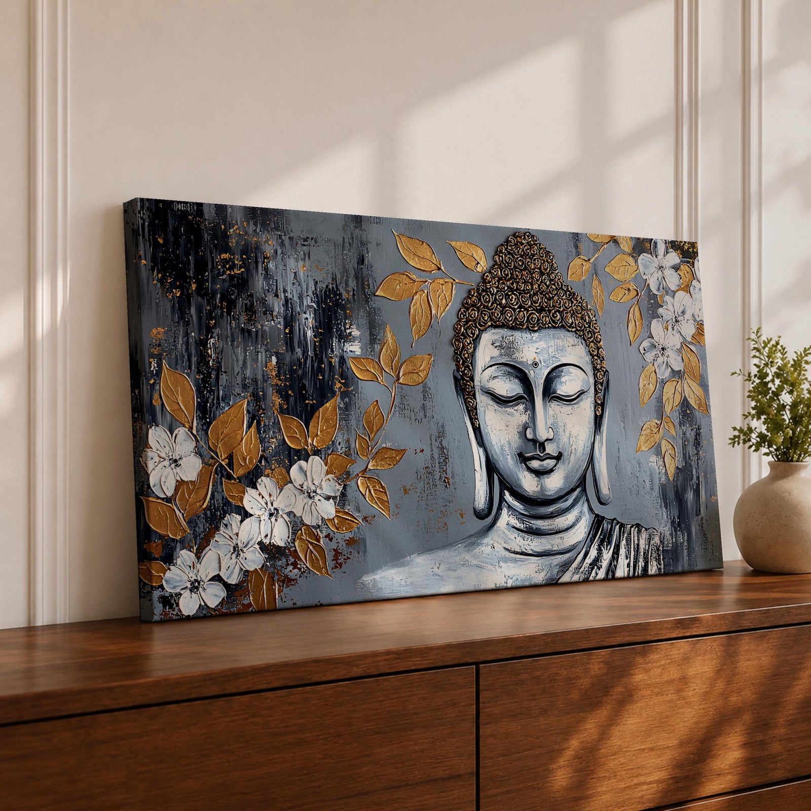 Panoramic painting of a serene Buddha portrait with closed eyes rendered in textured gray and gold tones. The composition features golden leaves and white blossoms surrounding the calm face, with layered brushstrokes and metallic accents creating contrast against a dark abstract background.