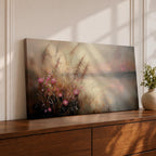 Panoramic landscape painting of soft pink wildflowers and tall grasses growing along a calm lakeshore. The scene features delicate meadow blooms in the foreground with textured brushstrokes and warm earthy tones, fading into a misty reflective lake and distant horizon under a gentle sky.