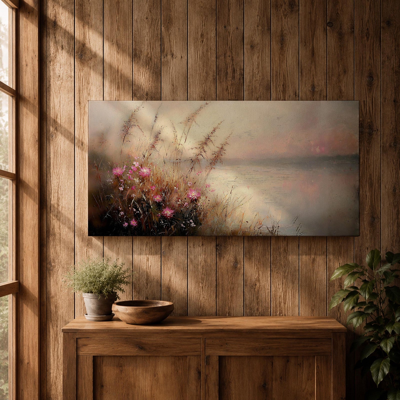 Panoramic landscape painting of soft pink wildflowers and tall grasses growing along a calm lakeshore. The scene features delicate meadow blooms in the foreground with textured brushstrokes and warm earthy tones, fading into a misty reflective lake and distant horizon under a gentle sky.