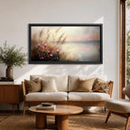 Panoramic landscape painting of soft pink wildflowers and tall grasses growing along a calm lakeshore. The scene features delicate meadow blooms in the foreground with textured brushstrokes and warm earthy tones, fading into a misty reflective lake and distant horizon under a gentle sky.