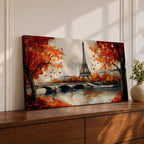 Panoramic painting of the Eiffel Tower rising above the Seine River with an arched stone bridge and classic Parisian buildings along the waterfront. Vibrant red and orange autumn trees frame the scene while textured brushstrokes reflect warm foliage and architecture across the calm river surface.