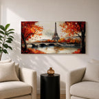 Panoramic painting of the Eiffel Tower rising above the Seine River with an arched stone bridge and classic Parisian buildings along the waterfront. Vibrant red and orange autumn trees frame the scene while textured brushstrokes reflect warm foliage and architecture across the calm river surface.