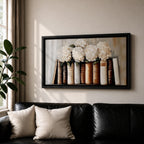 Panoramic still life painting of white hydrangea flowers arranged inside stacked vintage books with neutral beige and cream tones in a soft textured background.