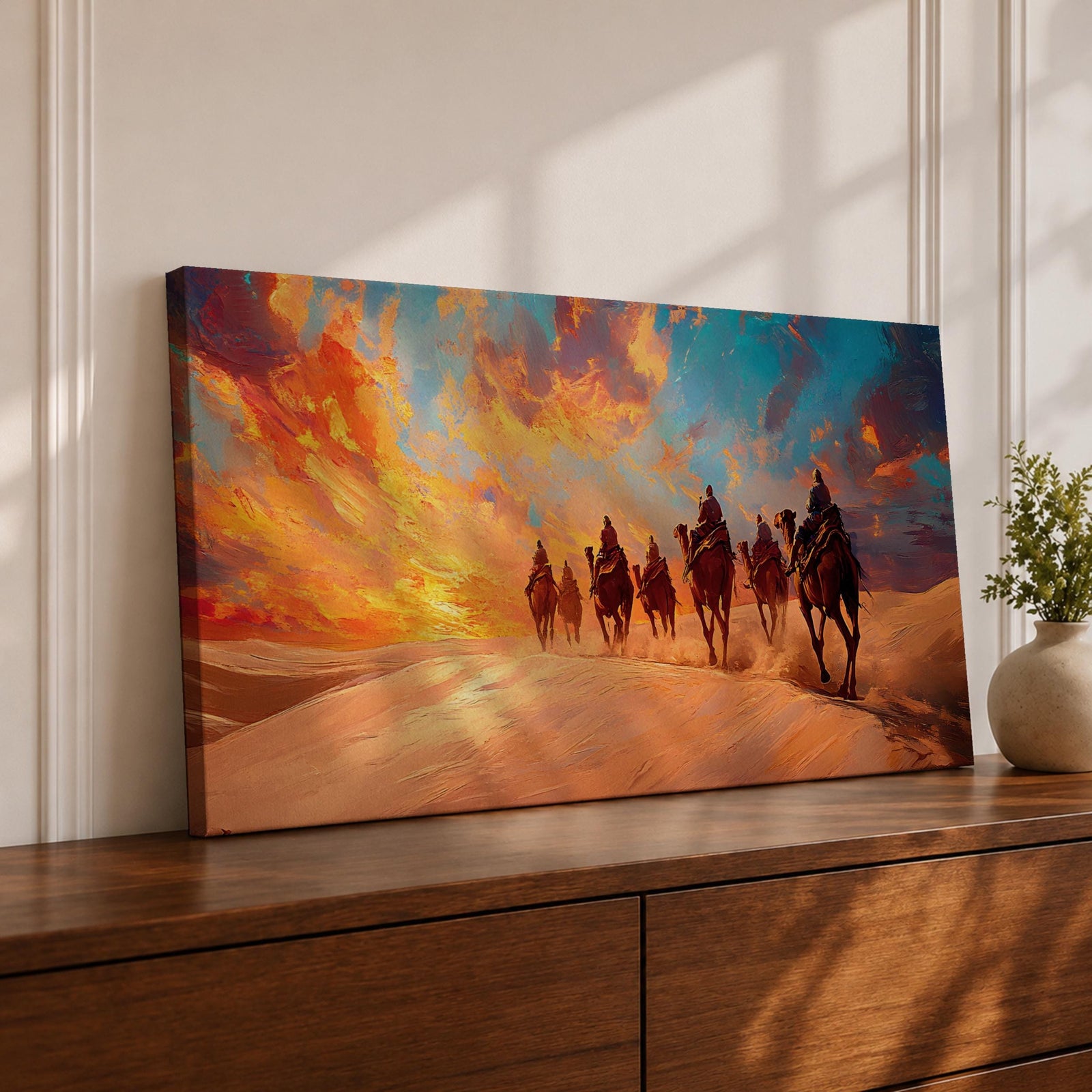 Panoramic painting of a camel caravan traveling across golden desert dunes at sunset with riders silhouetted beneath a vibrant dramatic sky.