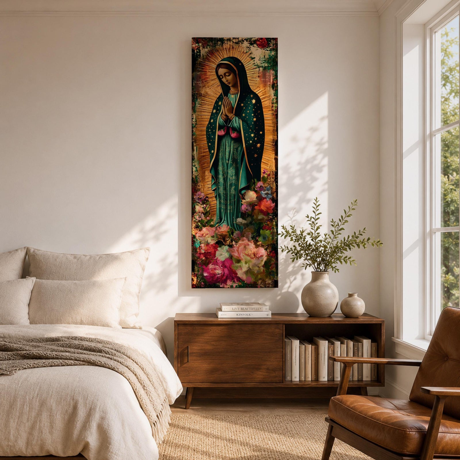 A tall narrow vertical painting of the Virgin Mary Guadalupe shown in prayer with hands clasped, wearing a deep teal mantle adorned with gold stars and a soft pink dress, surrounded by radiant golden rays, with rich floral elements in vibrant pink, red, and cream tones at the base, rendered in a textured painterly style with warm, aged tones.