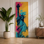 A tall narrow artwork of the Statue of Liberty shown from a low angle with the torch raised, rendered in bold pop art style with vibrant teal tones contrasted by bright pink and yellow paint splashes, featuring dynamic splatter textures and graphic shading in a modern abstract urban composition.