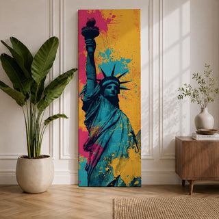 A tall narrow artwork of the Statue of Liberty shown from a low angle with the torch raised, rendered in bold pop art style with vibrant teal tones contrasted by bright pink and yellow paint splashes, featuring dynamic splatter textures and graphic shading in a modern abstract urban composition.