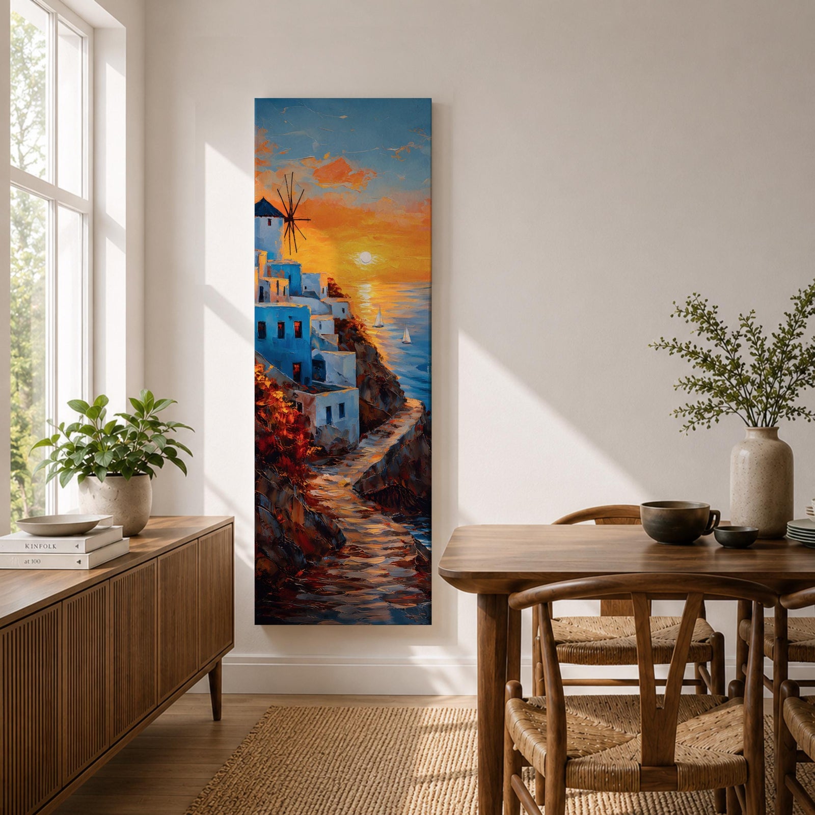 A tall vertical painting depicts a Santorini coastal scene with whitewashed buildings perched along a cliffside, a winding stone path leading toward the sea, and a glowing sunset casting warm orange and gold light across the sky and water, with a windmill silhouette and small sailboats adding depth to the vibrant Mediterranean composition.