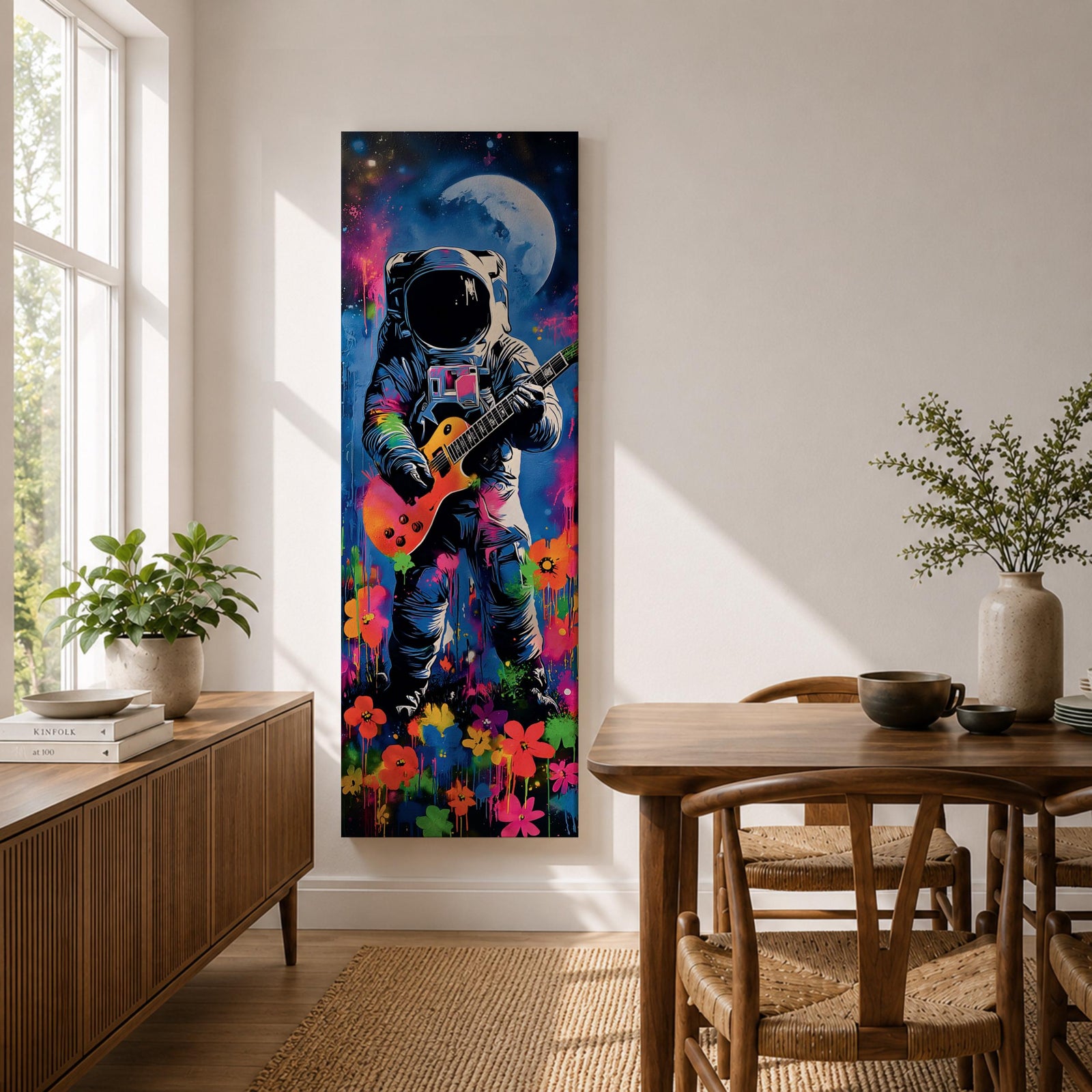 A tall vertical artwork shows an astronaut in a detailed space suit playing an electric guitar, set against a vivid cosmic backdrop with a glowing moon, deep blue sky, and splashes of neon pink, green, and orange paint, while bright flowers bloom at the base, blending surreal space imagery with street art style and bold expressive color.