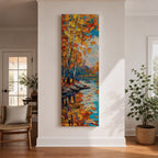 Tall vertical landscape painting of slender birch trees with golden autumn leaves along a calm reflective river. Thick palette knife oil brushstrokes create vibrant fall colors of orange, yellow, and blue with the trees mirrored in the water while distant forest and sky appear softly textured in the background.