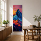 Tall vertical abstract mountain painting with bold colorful peaks in vibrant blue, red, purple, and yellow tones. Thick impasto brushstrokes create dramatic alpine ridges beneath a bright pink and orange sky, forming a modern expressive mountain landscape.