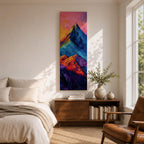 Tall vertical abstract mountain painting with bold colorful peaks in vibrant blue, red, purple, and yellow tones. Thick impasto brushstrokes create dramatic alpine ridges beneath a bright pink and orange sky, forming a modern expressive mountain landscape.