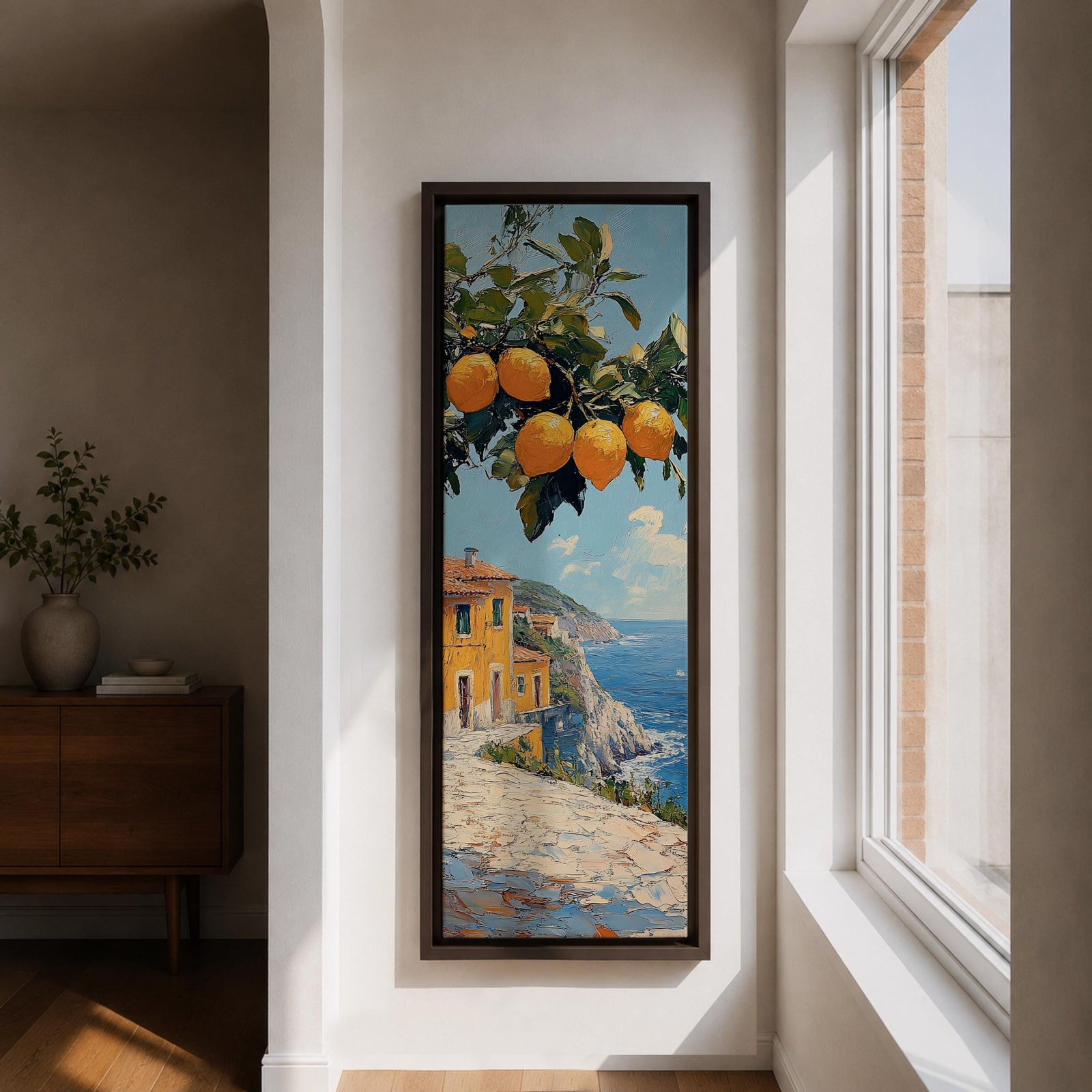 Tall vertical Mediterranean coastal painting showing bright yellow lemons hanging from a leafy branch above an Amalfi seaside village. Colorful Italian buildings sit along a cliffside path overlooking deep blue ocean waters beneath a sunny sky.