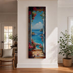Tall vertical coastal painting showing an Italian ocean view framed by an open doorway with pink flowers and potted plants. The bright Mediterranean sea stretches toward rocky cliffs and a distant sailboat beneath a clear blue sky.
