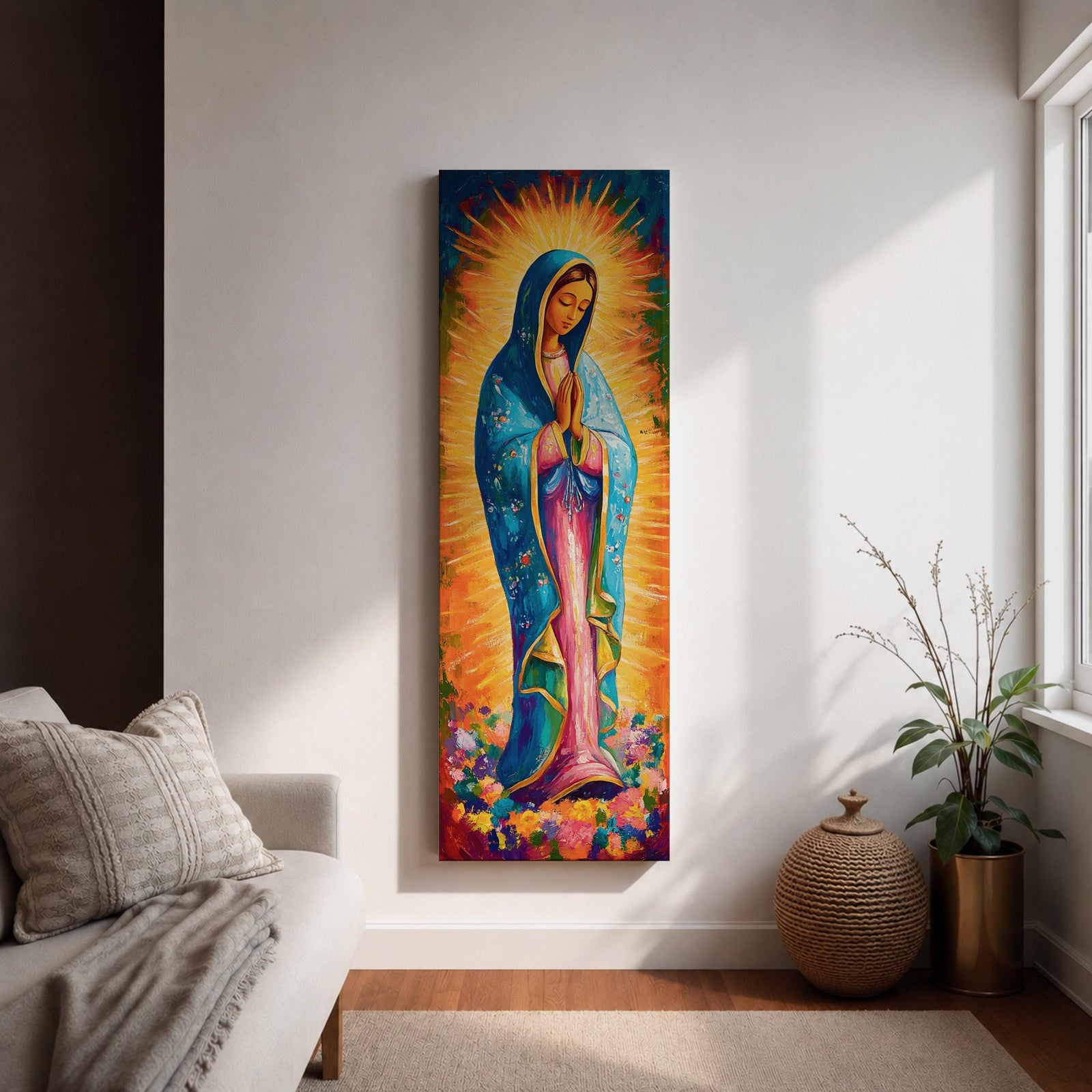 Long vertical painting of the Virgin Mary standing in prayer with hands together, wearing a blue mantle over a pink robe and surrounded by radiant golden rays. Colorful flowers gather at her feet while expressive brushstrokes and vibrant tones create a devotional depiction inspired by the Virgen de Guadalupe iconography.