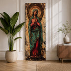 Long vertical painting of the Virgin Mary standing with hands clasped in prayer, wearing a deep red robe and teal mantle. An ornate circular golden halo with sacred symbols forms a radiant backdrop while textured brushwork and aged tones create a traditional Catholic devotional icon style composition.