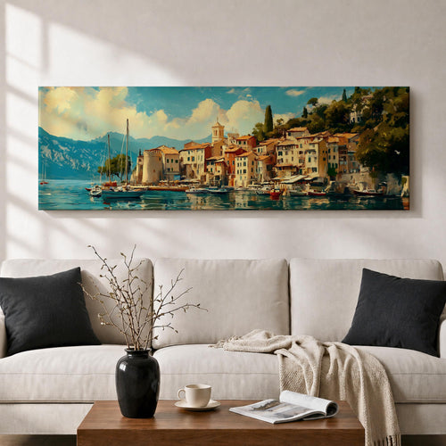 Panoramic coastal village painting showing colorful Mediterranean houses clustered along a harbor with sailboats resting on calm blue water. A small church tower rises above the waterfront while mountains and lush hills frame the background beneath a bright sky with soft clouds across the wide horizontal scene.