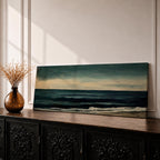 Panoramic seascape painting showing dark rolling waves beneath a dramatic cloudy sky with faint light breaking along the distant horizon. Deep teal and navy tones blend across the water while textured brushstrokes form soft foam along the shoreline, creating a moody minimalist coastal composition across the wide horizontal canvas.