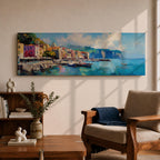 Panoramic Mediterranean harbor village painting featuring colorful seaside houses along a stone waterfront with small fishing boats resting in calm blue water. Soft clouds drift above distant cliffs and green hills while textured brushstrokes capture reflections and gentle movement across the wide coastal scene.