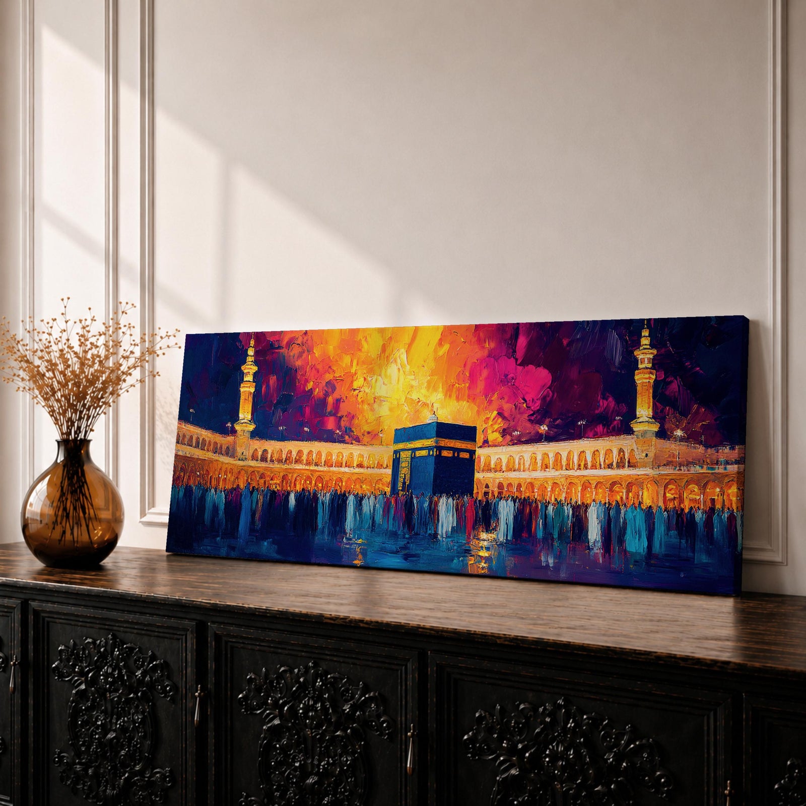 Panoramic painting of the Kaaba at Masjid Al Haram in Mecca surrounded by worshippers within the illuminated mosque courtyard. Tall minarets rise on either side while glowing sunset colors of gold, magenta, and deep blue fill the sky above the sacred Islamic landmark across the wide horizontal composition.