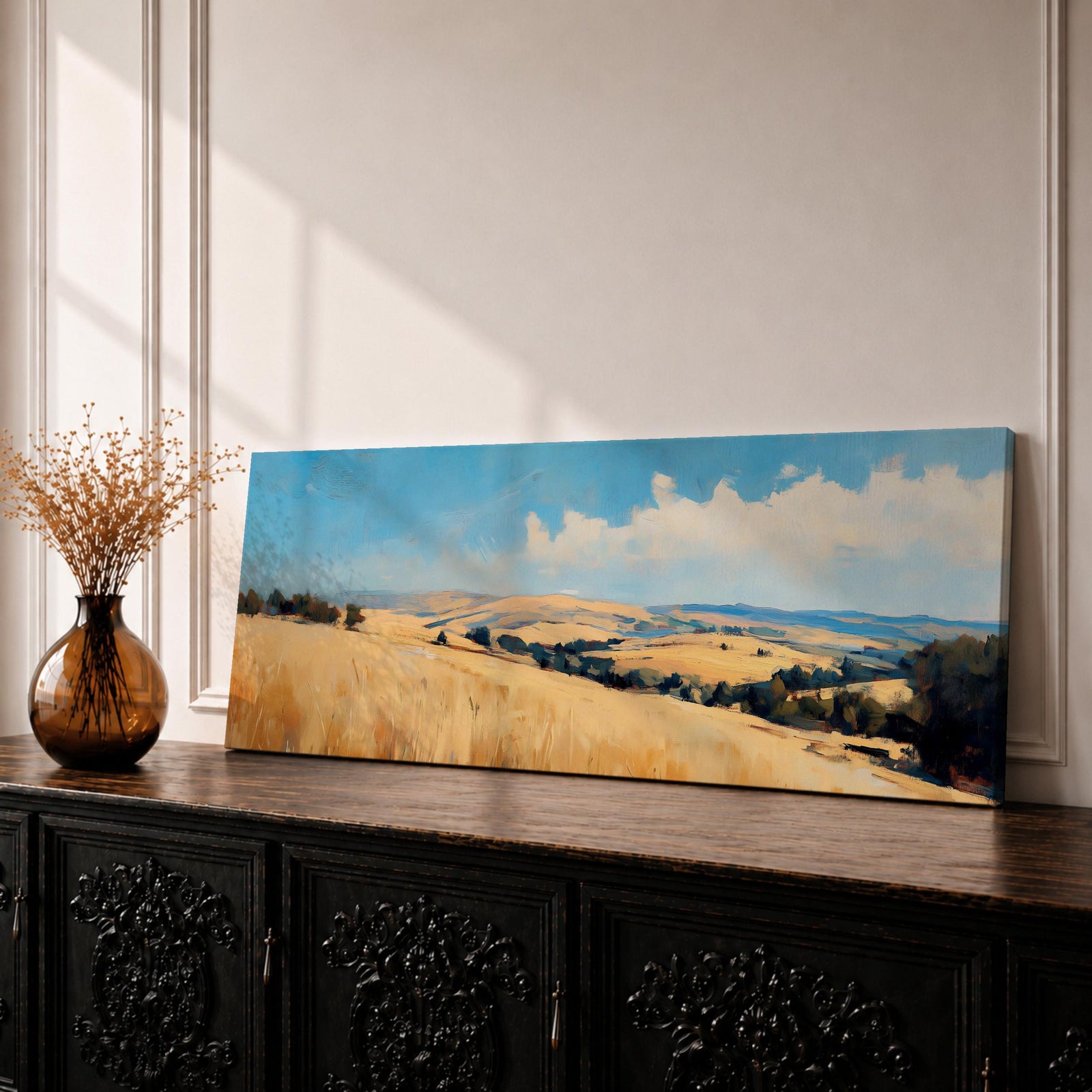 Panoramic wheat field landscape painting showing rolling golden farmland stretching across hills beneath a bright blue sky with scattered clouds. Textured brushstrokes depict tall wheat grasses in the foreground leading toward layered countryside fields, tree clusters, and distant hills across the wide rural horizon.