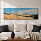 Panoramic wheat field landscape painting showing rolling golden farmland stretching across hills beneath a bright blue sky with scattered clouds. Textured brushstrokes depict tall wheat grasses in the foreground leading toward layered countryside fields, tree clusters, and distant hills across the wide rural horizon.